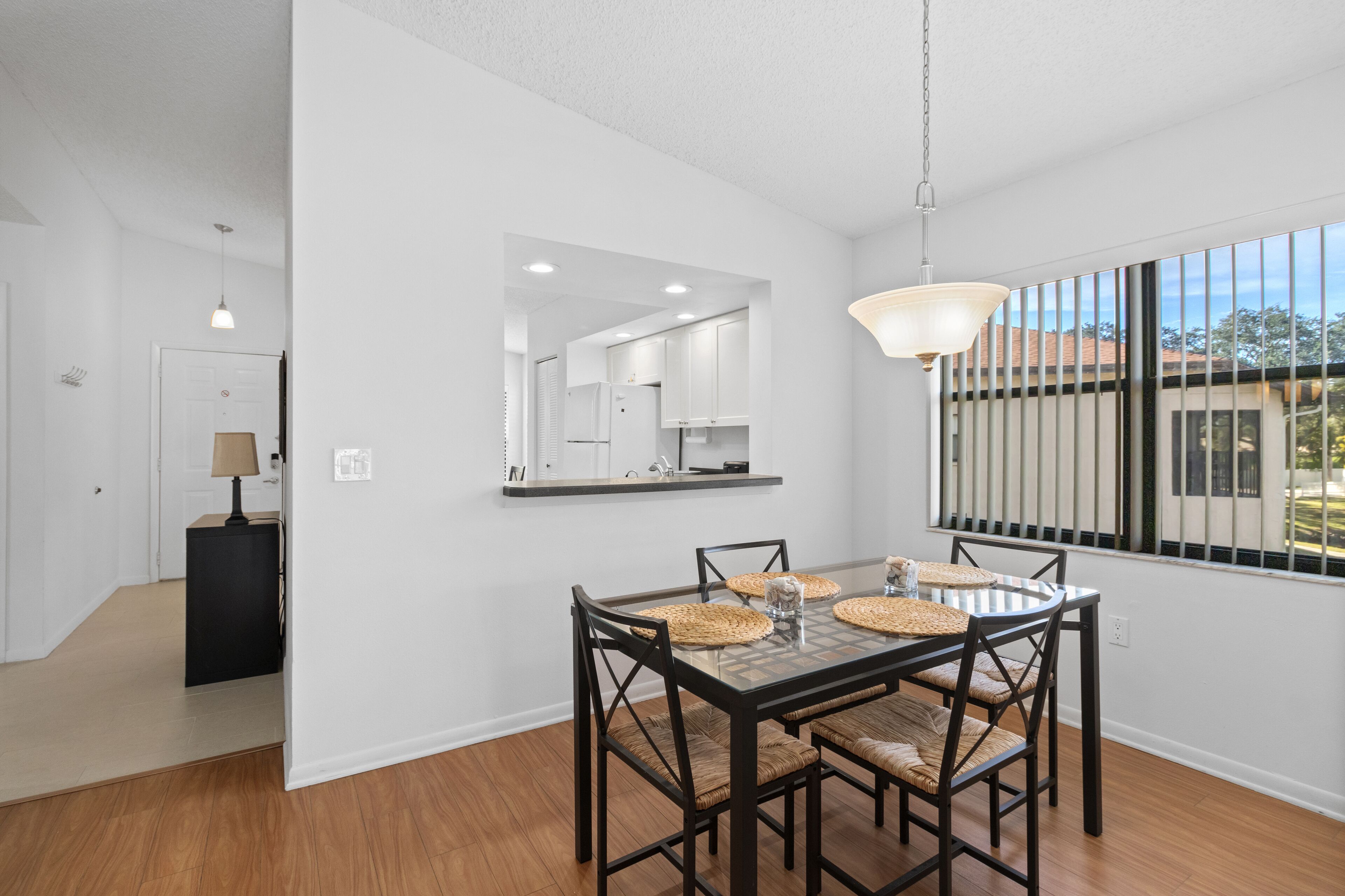 A dining area with a glass table, woven placemats, and dark chairs.