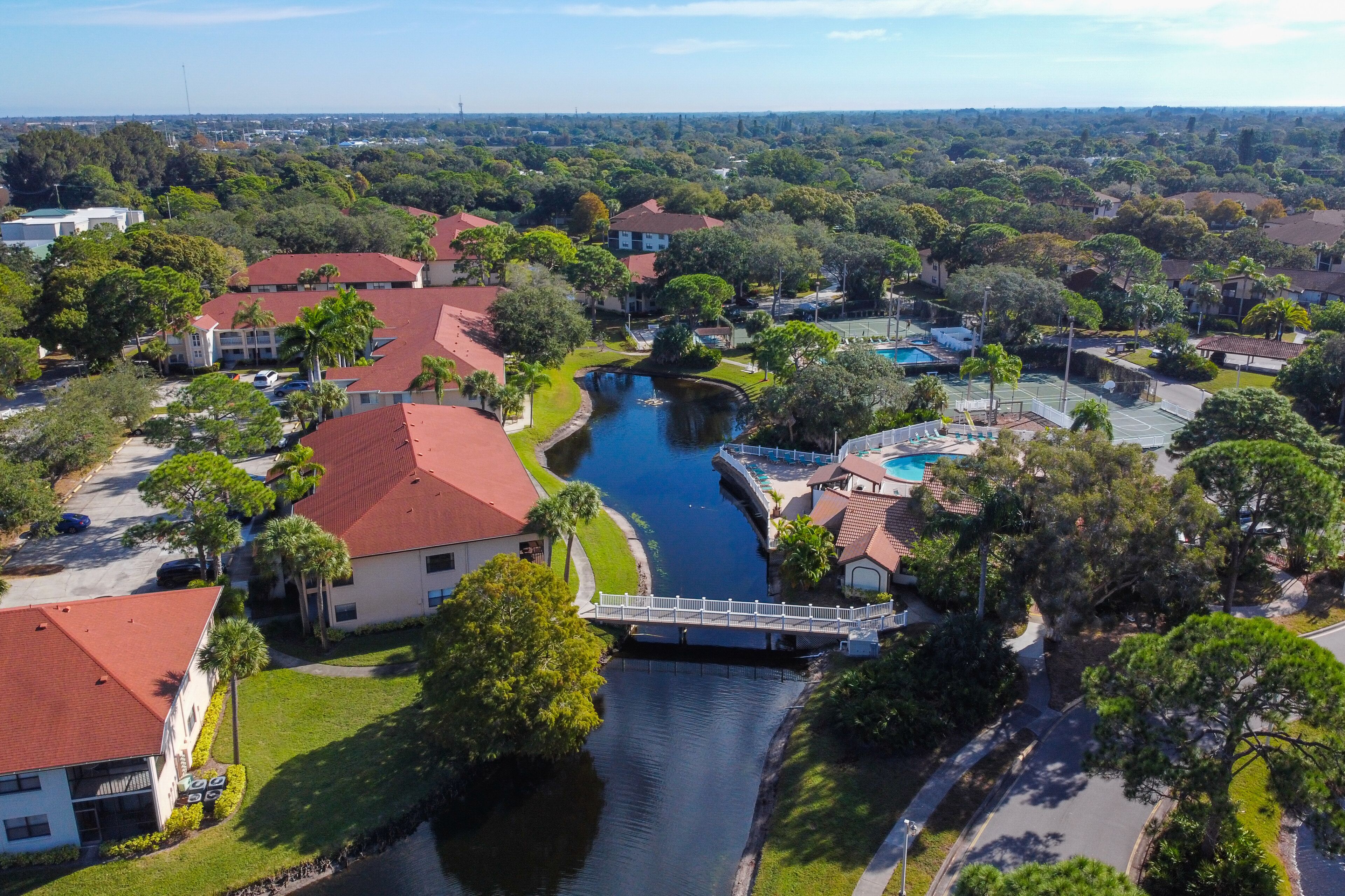 A residential area with a canal, houses with red roofs, and a bridge.