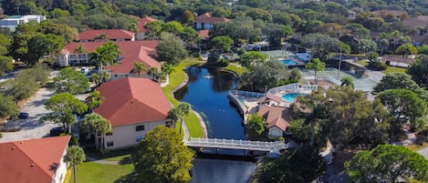 A residential area with a canal, houses with red roofs, and a bridge.