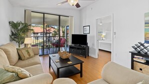 Una sala de estar con un sofá, mesa de centro, televisor y ventilador de techo.
