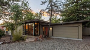 A modern house with a garage, a gravel driveway, and a large tree in front. - Sedona Modern Mid-Century Walk to Hiking Trails, Natural Light, Dinner In The Yard! (Sedona)