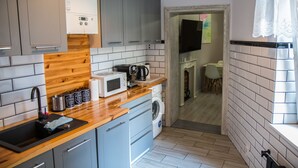 Una cocina compacta con armarios grises, encimera de madera, microondas integrado y lavadora.