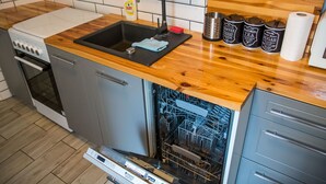 Una cocina con encimera de madera, un fregadero, lavavajillas y armarios.