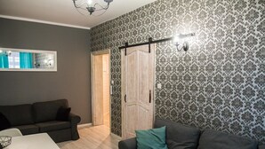 Una sala de estar con un sofá gris, una mesa blanca y un papel tapiz estampado.