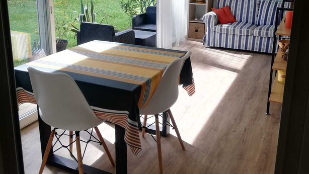 A modern living room with a dining area, large windows, and a view of a garden. - Apartment Château d'Arcadie, 67m2, terrace and garage. The whole of Biarritz on foot! (Biarritz)