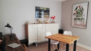 A modern living room with a wooden table, white chairs, a white cabinet, and a painting of birds. - Apartment Château d'Arcadie, 67m2, terrace and garage. The whole of Biarritz on foot! (Biarritz)