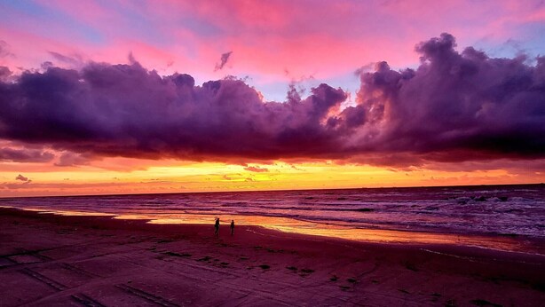 Una playa con un atardecer y nubes.
