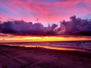 Een strand met een zonsondergang en wolken.