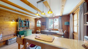 A cozy kitchen with wooden beams, a green cabinet, a wooden table, and a cutting board. - Charming Chalet - Walk to Piste & Villars Centre! Style & Comfort 5 Bed/4 Bath! (Ollon)