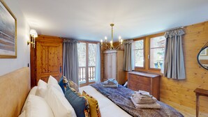 A cozy bedroom with a bed, wooden wardrobe, and a window with curtains. - Charming Chalet - Walk to Piste & Villars Centre! Style & Comfort 5 Bed/4 Bath! (Ollon)