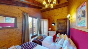 A wooden cabin room with a bed, a dresser, a mirror, and a door. - Charming Chalet - Walk to Piste & Villars Centre! Style & Comfort 5 Bed/4 Bath! (Ollon)
