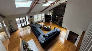 A spacious living room with a large sectional sofa, a fireplace, and skylights. - Strawberry Hill A Deluxe Retreat, Close to Village 1.5 mi to Acadia (Bar Harbor)