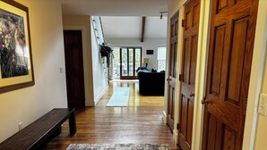 A hallway with wooden flooring, a bench, a rug, and a door. - Strawberry Hill A Deluxe Retreat, Close to Village 1.5 mi to Acadia (Bar Harbor)