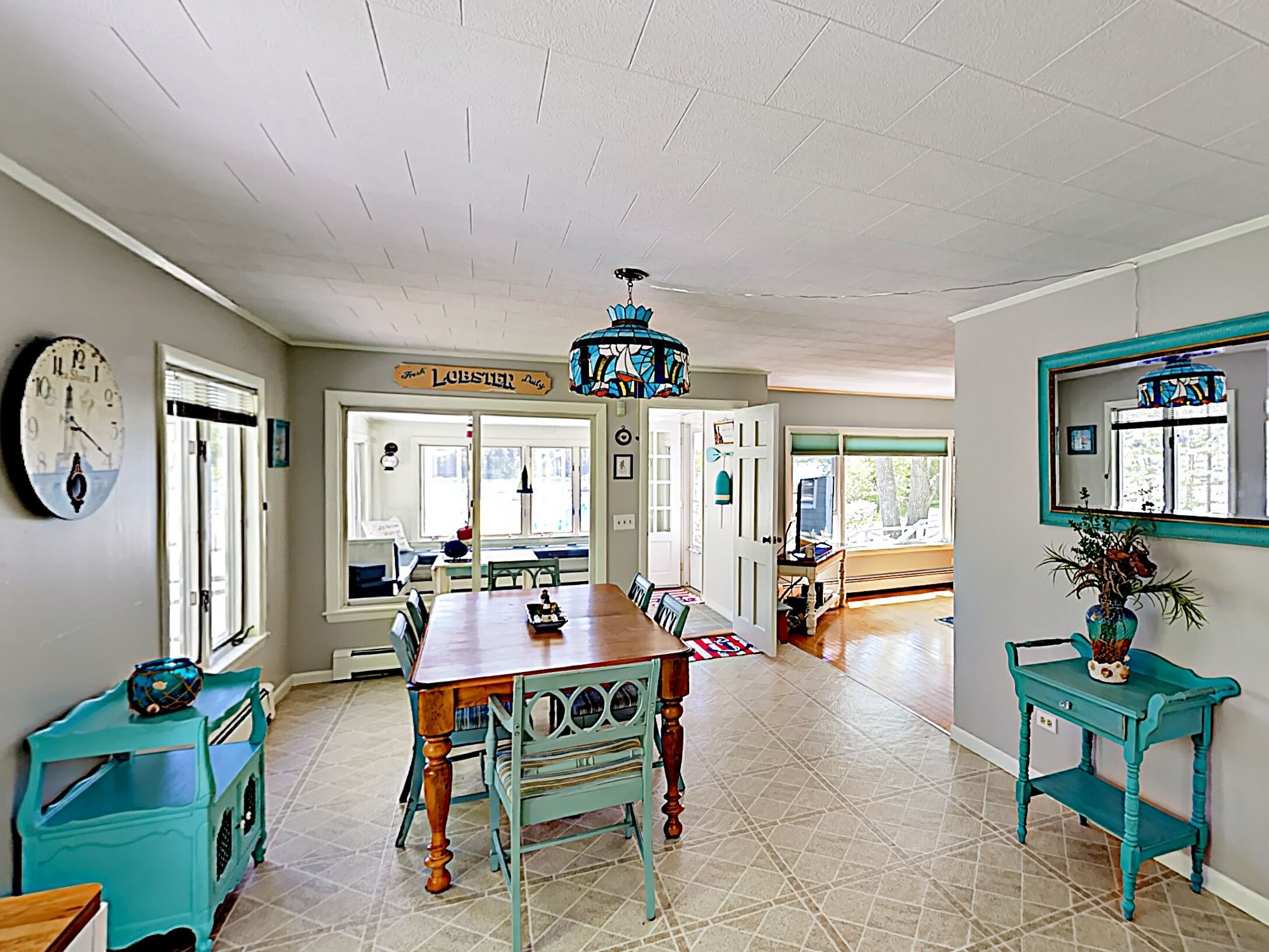 A spacious kitchen with a wooden table, teal furniture, and a hanging chandelier.