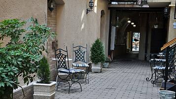Un cortile con sedute all'aperto, fioriere in pietra e pavimento in mattoni.