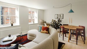 A living room with a sofa, a coffee table, a dining table with chairs, and a radiator. - 74-78 Marylebone Lane (London)