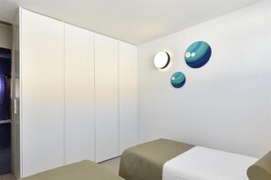Una habitación moderna con armario corredero, cama con cabecero color beige y dos lámparas esféricas fijadas a la pared.