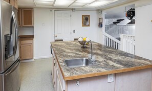 A kitchen with a granite countertop, stainless steel sink, and wooden cabinets.