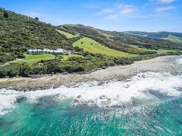 A coastal landscape with a beach, rolling hills, and a small cluster of buildings. - 3 Whitecrest Resort - Pool & Amazing Ocean Views (Wongarra)