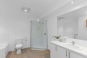 Ein modernes Badezimmer mit Glasdusche, Toilette, Waschbecken und einem großen Spiegel.