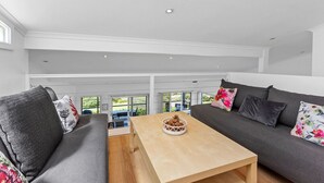A modern living room with a sofa set, a coffee table, and a view of the outdoors. - 5 Whitecrest Resort - Pool & Amazing Ocean Views (Wongarra)