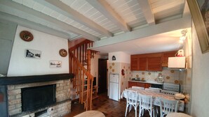 Ein gemütliches Wohnzimmer mit Kamin, einer Holztreppe und einem Essbereich mit Tisch und Stühlen.
