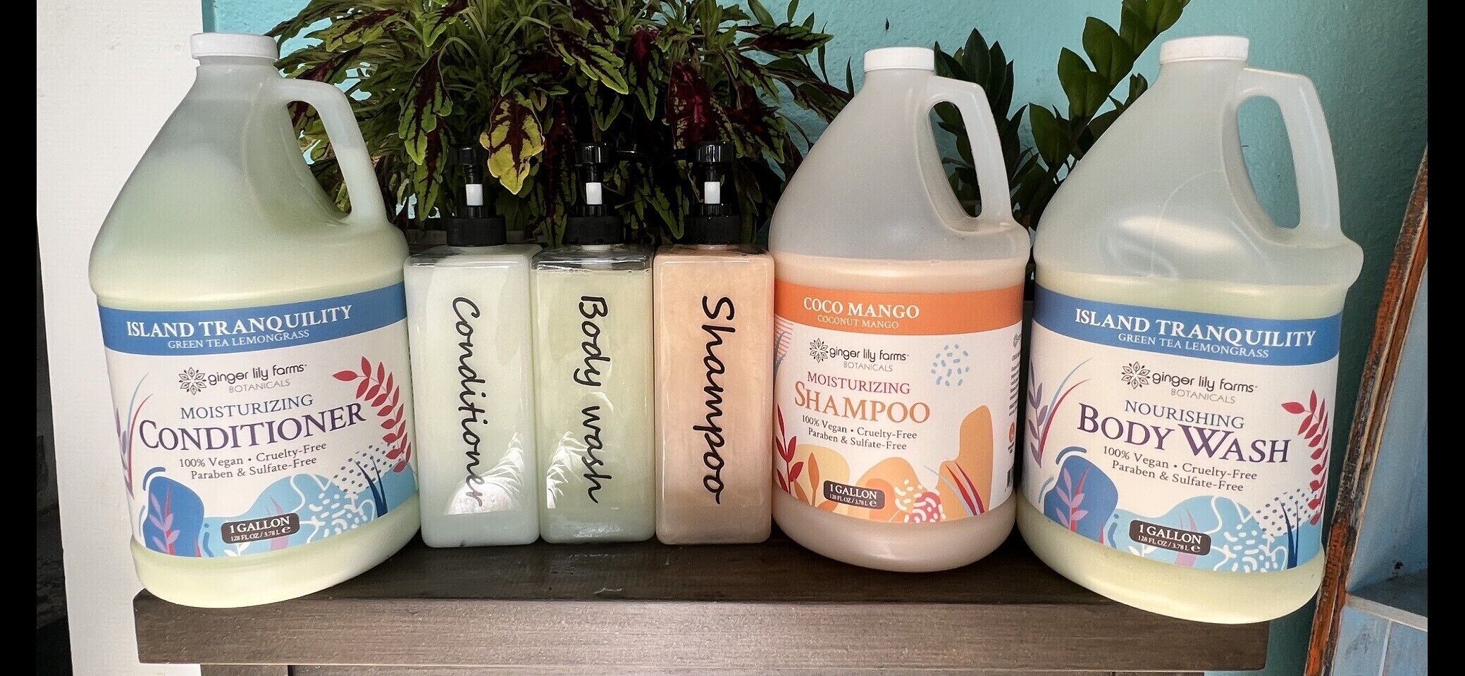 A shelf with five bottles of Island Tranquility body wash and conditioner, including a shampoo and a body wash.