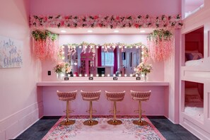A pink-themed room with a vanity mirror, four bar stools, and a floral arrangement. - Spacious Pink Palace townhome near The Gulch with rooftop and balcony (Nashville)