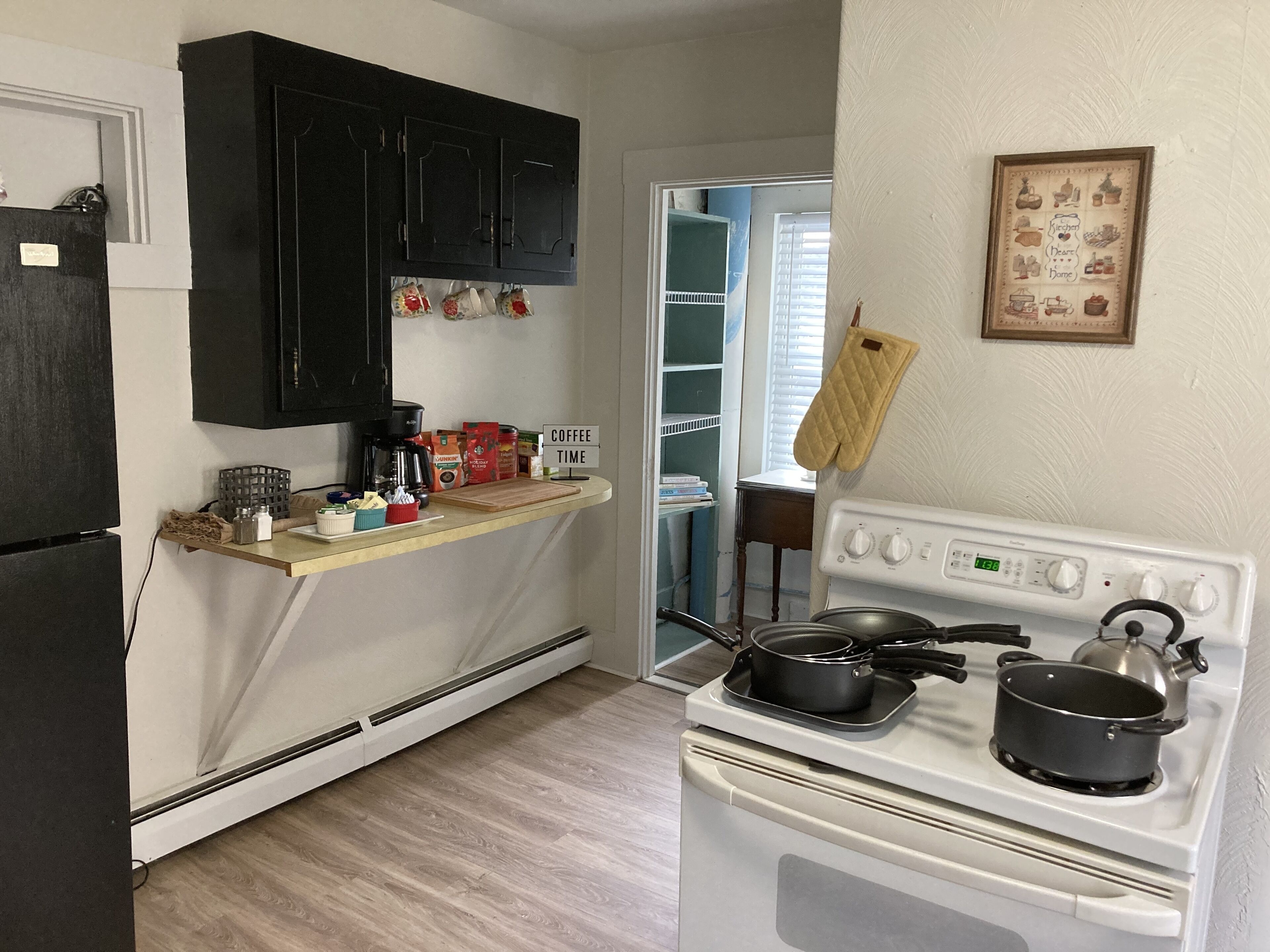 A kitchen with a stove, a coffee station, and a refrigerator.