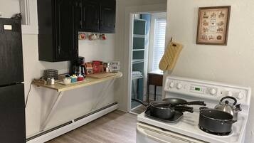 A kitchen with a stove, a coffee station, and a refrigerator.