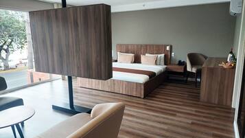 Una habitación de hotel moderna con una cama grande, un escritorio, una silla y un sofá.