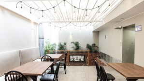A restaurant with wooden tables and black chairs, a brick fireplace, and string lights on the ceiling. - Equo Hotel Boutique (Lima)