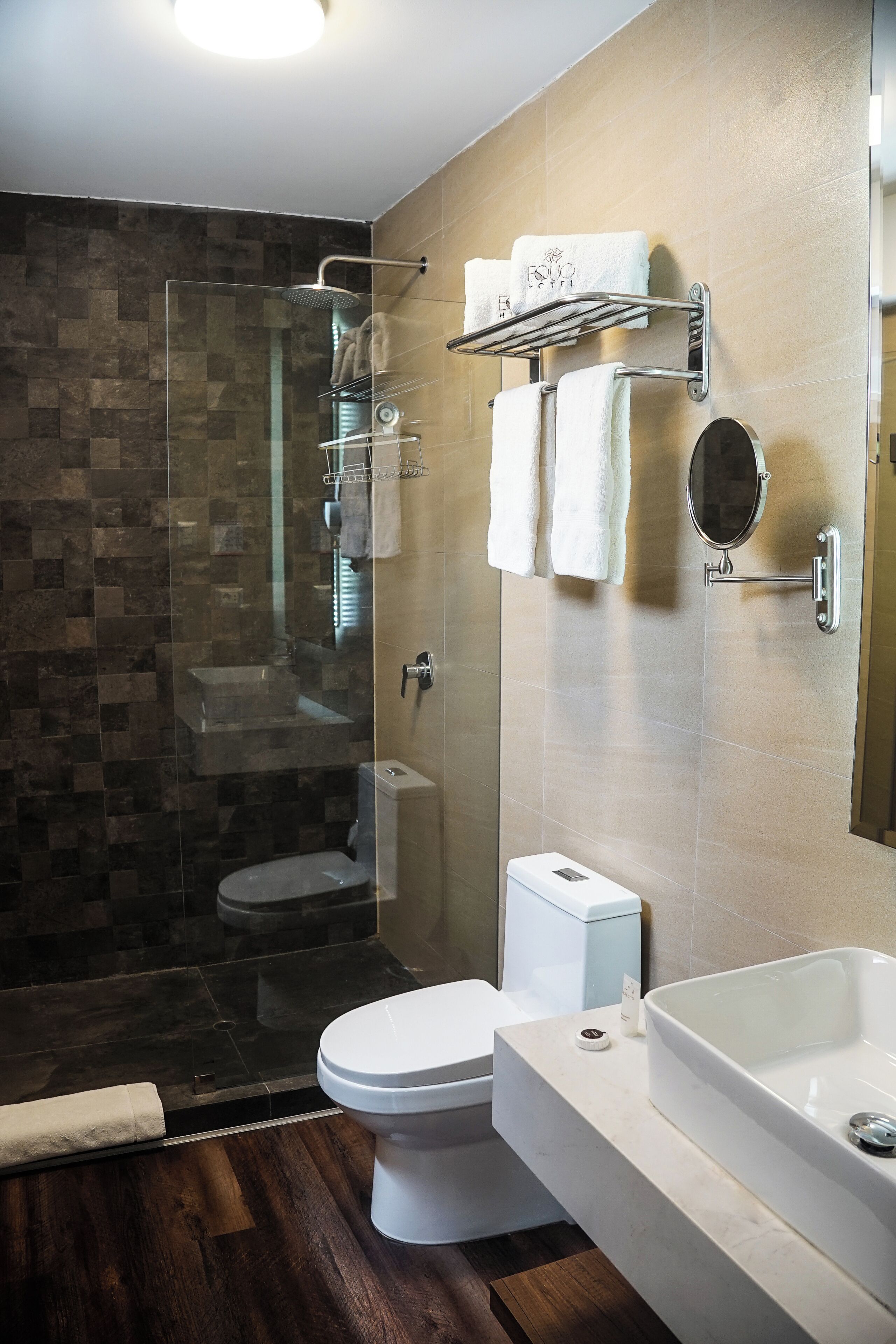A modern bathroom with a glass-enclosed shower, a toilet, and a large bathtub.