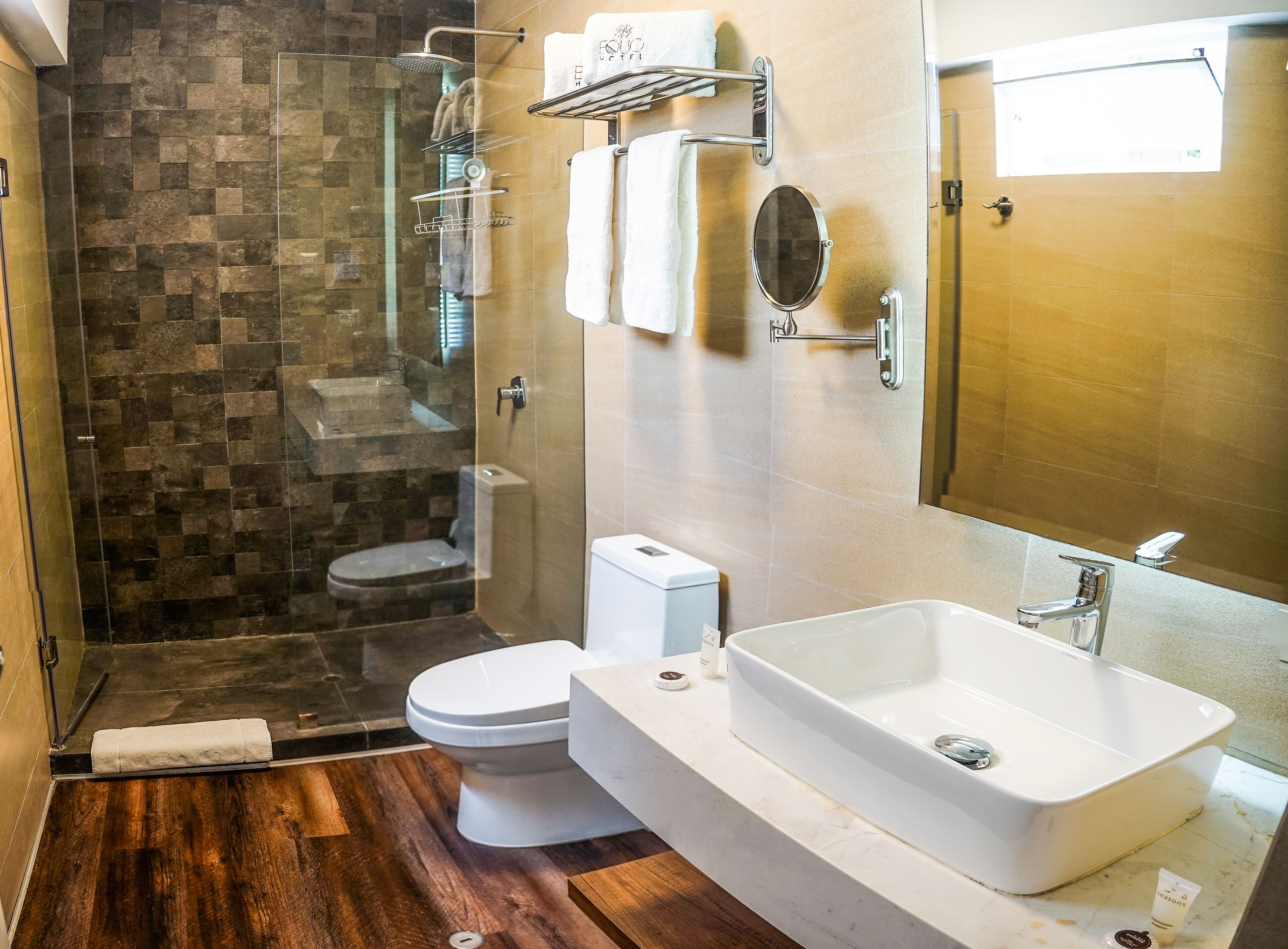 A modern bathroom with a glass-enclosed shower, a white toilet, and a large white sink.