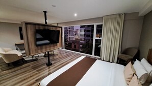 A modern hotel room with a large bed, a flat-screen TV, a sofa, and a large window with a city view. - Equo Hotel Boutique (Lima)