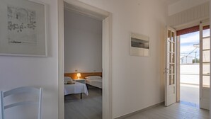 A hotel room with two beds, a nightstand, a chair, and a door leading to a balcony. - VILLA ISCHIA - Villa a few meters from the sea (Torre Suda)