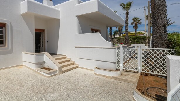 A white building with a staircase leading to a door, surrounded by palm trees and a clear sky. - VILLA ISCHIA - Villa a few meters from the sea (Torre Suda)