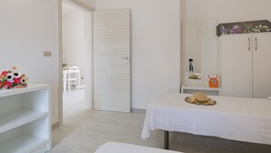 A bedroom with a bed, a dresser, a vanity, and a door leading to another room. - VILLA ISCHIA - Villa a few meters from the sea (Torre Suda)
