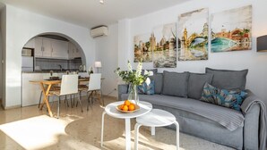 A modern living room with a grey sofa, a dining table with chairs, a vase with flowers, and two wall-mounted paintings. - SHR004 Smile Beach House. Incredible views. (Nerja)