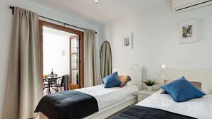 A hotel room with two beds, a dining area with a table and chairs, and a view through a glass door. - SHR004 Smile Beach House. Incredible views. (Nerja)