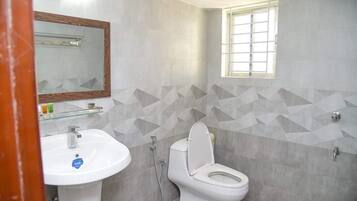 Casa de banho com lavatório branco, sanita e chuveiro.