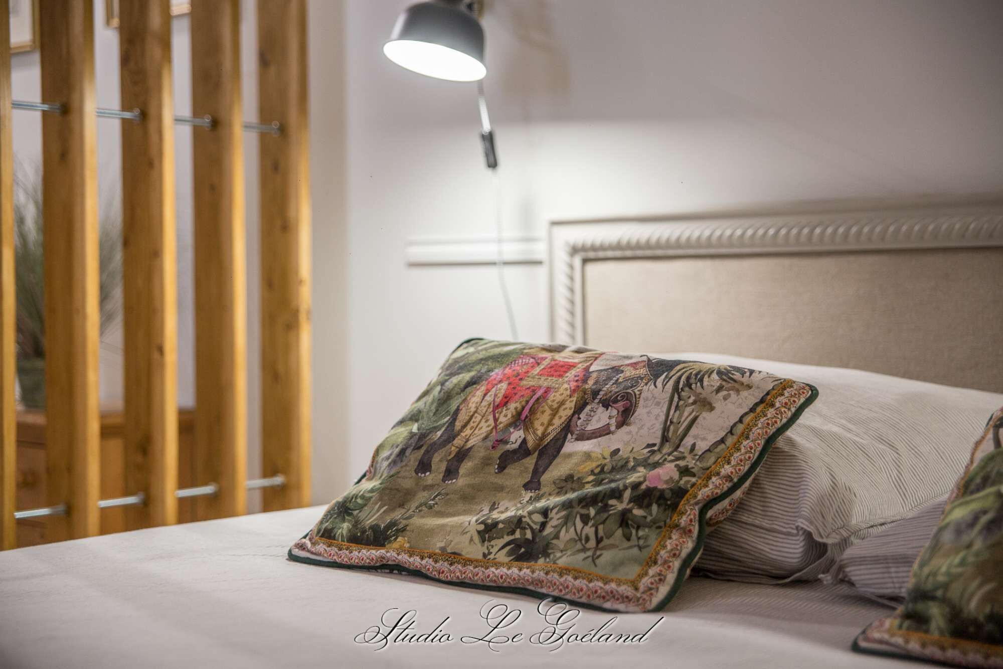 Een bed met decoratief kussen en hoofdbord.