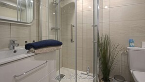 Une salle de bain moderne avec une douche à parois de verre, un lavabo blanc et des toilettes.