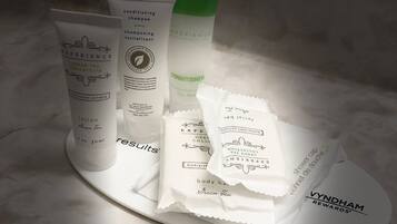 A tray with various toiletries including a conditioner, lotion, and shower cap.