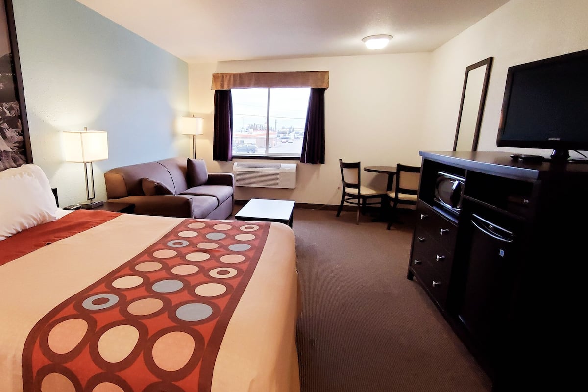 Una habitación de hotel con cama, escritorio, televisión y vistas al exterior.
