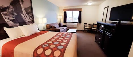 Een hotelkamer met een bed, een bureau, een televisie en uitzicht.