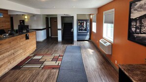 A hotel lobby with a reception desk, a vending machine, and a hallway leading to a door. - Westlake Inn (Strathmore)