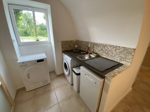 Enjoy cooking in this well-equipped kitchen with a washer and dryer, stainless steel sink, and window overlooking the surrounding greenery.