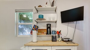 A kitchenette with a coffee maker, a toaster, and a flat-screen TV mounted on the wall. - Private Tiny House Retreat with Spacious Patio, Free Parking & WiFi (Las Vegas)