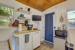 Una cocina con techo de madera, un televisor sobre la encimera, un microondas y una ventana con vistas a zonas verdes.